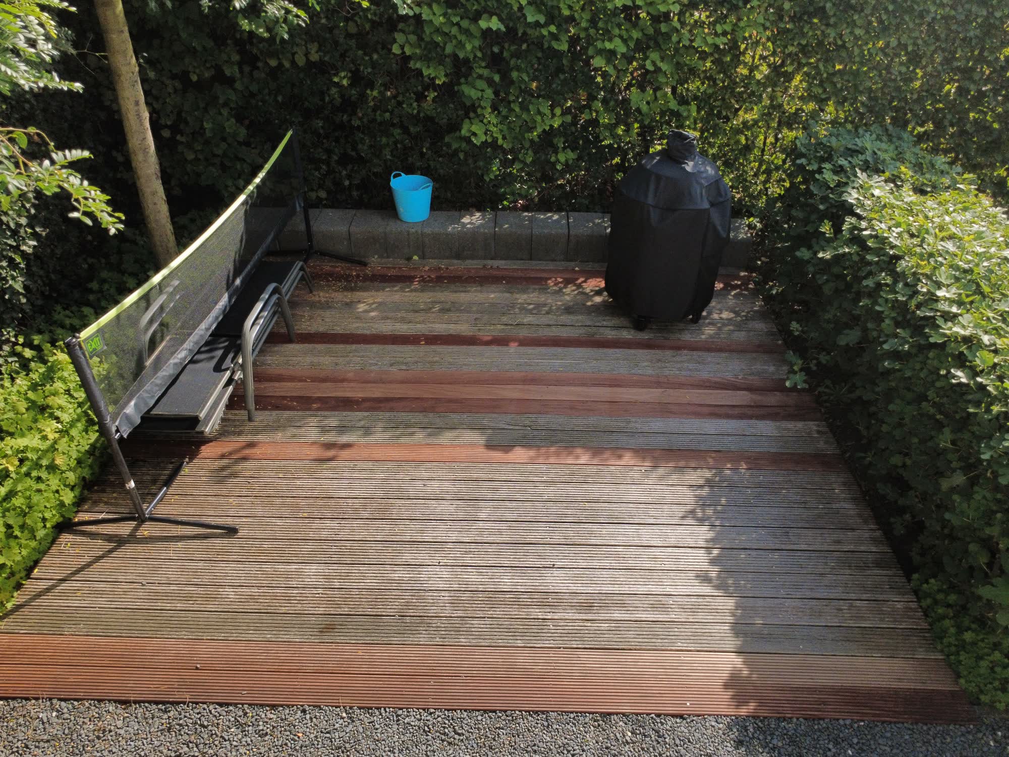 Houten vlonder achter in de tuin met een barbecue