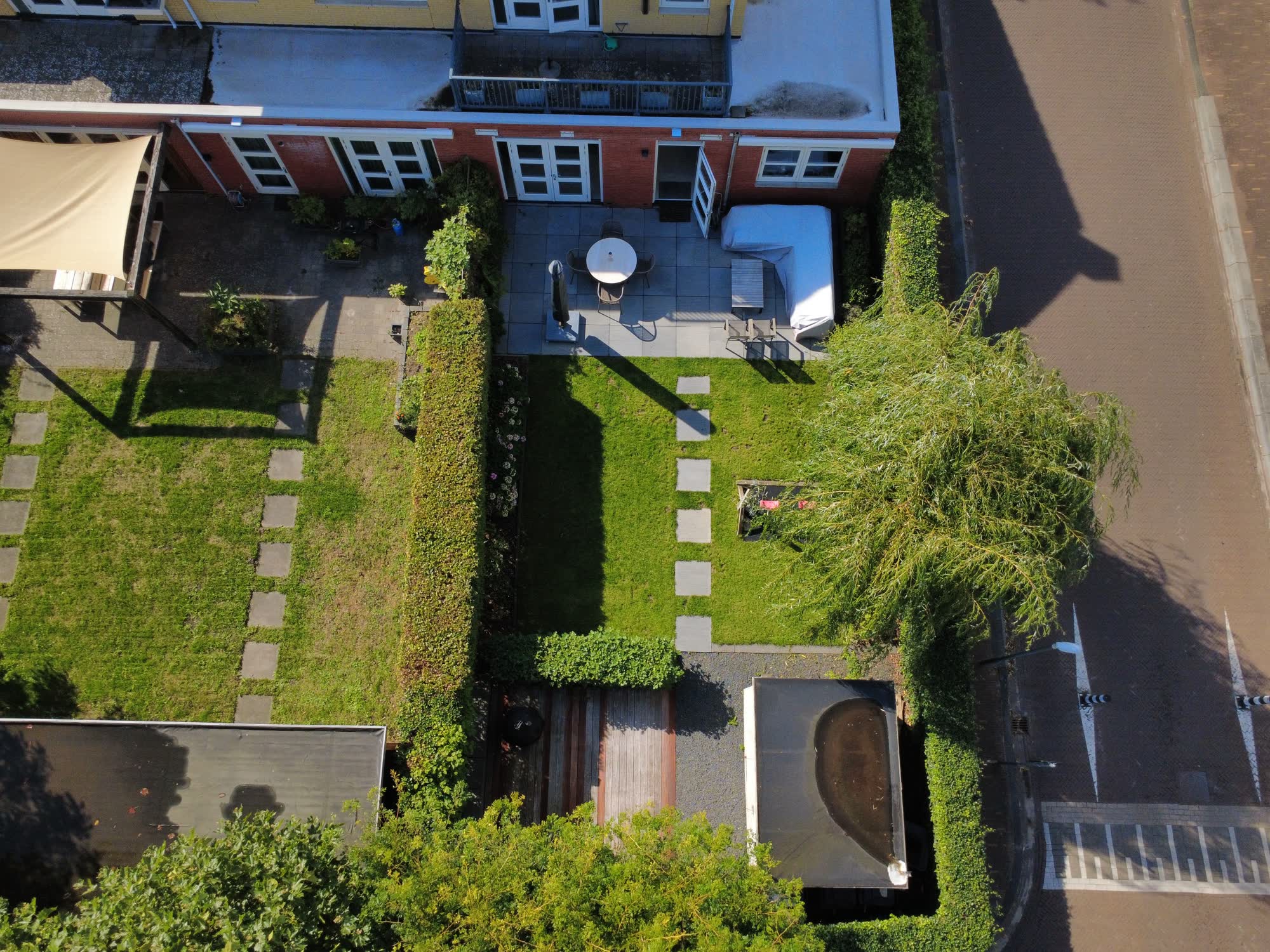 Achtertuin met terras, gras en tegelpad, recht van boven