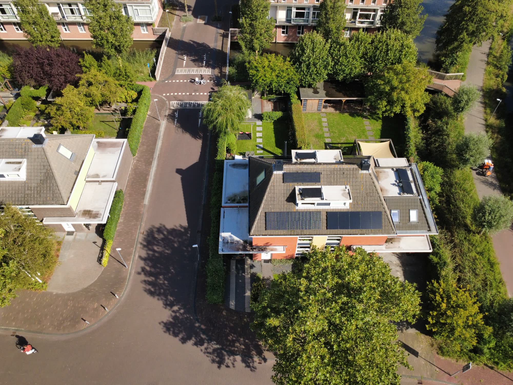 Het huis van de zijkant, met water en appartementen erachter